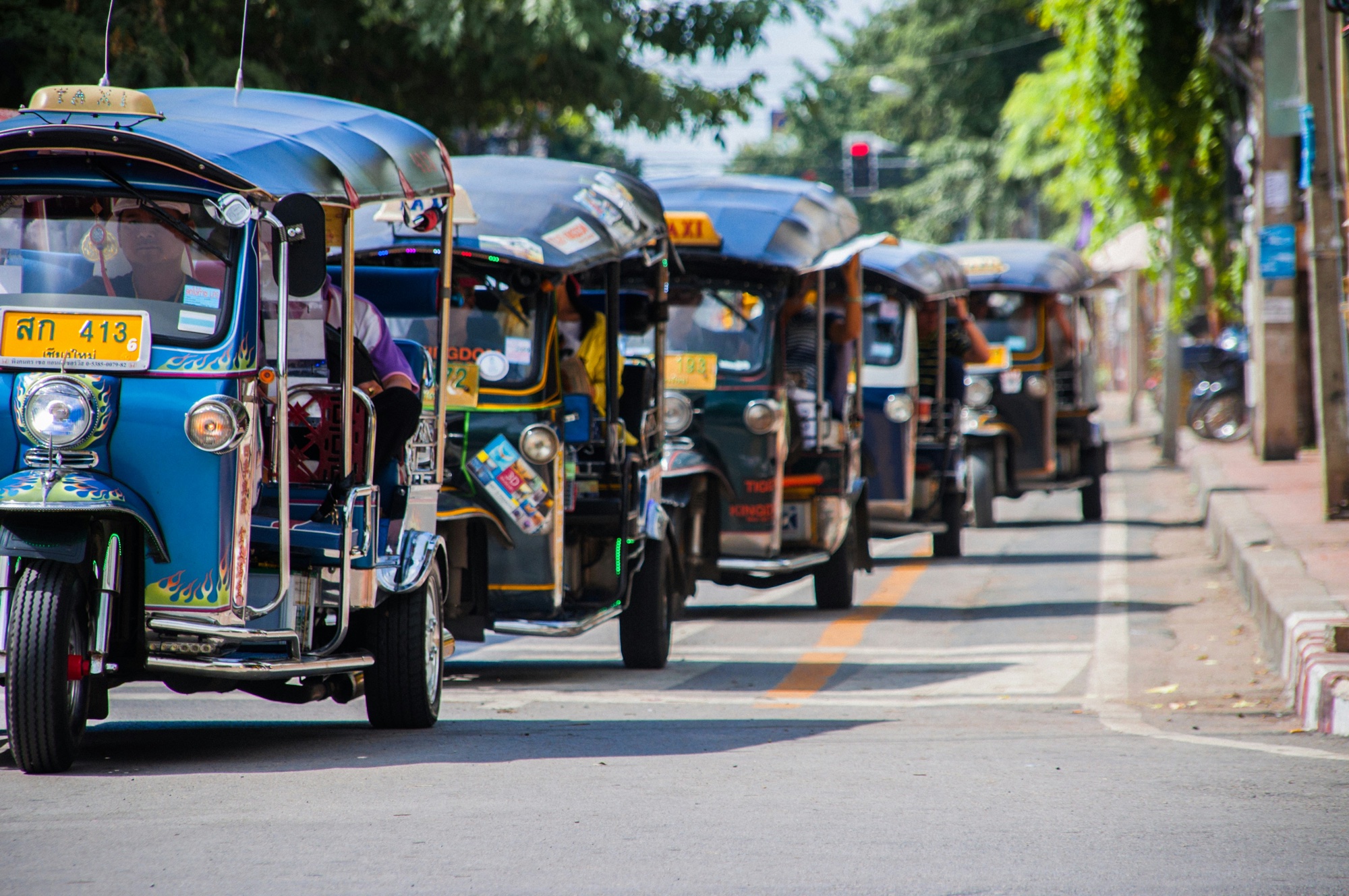 A line of tuk-tuks waiting curbside on a Thai street